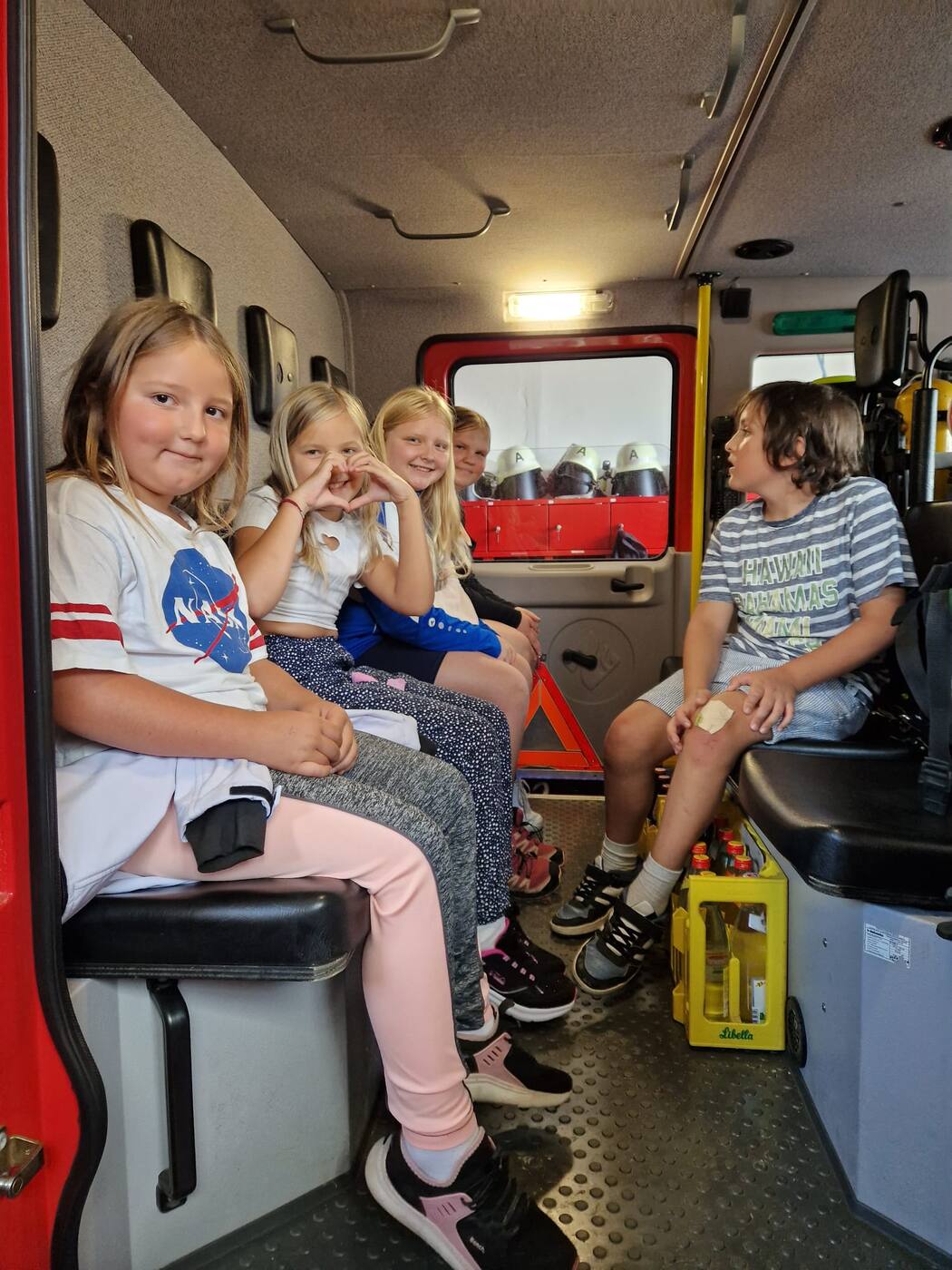 Kinder der Kinderfeuerwehr Triefenried sitzen gut gelaunt im Mannschaftsraum des Feuerwehrautos